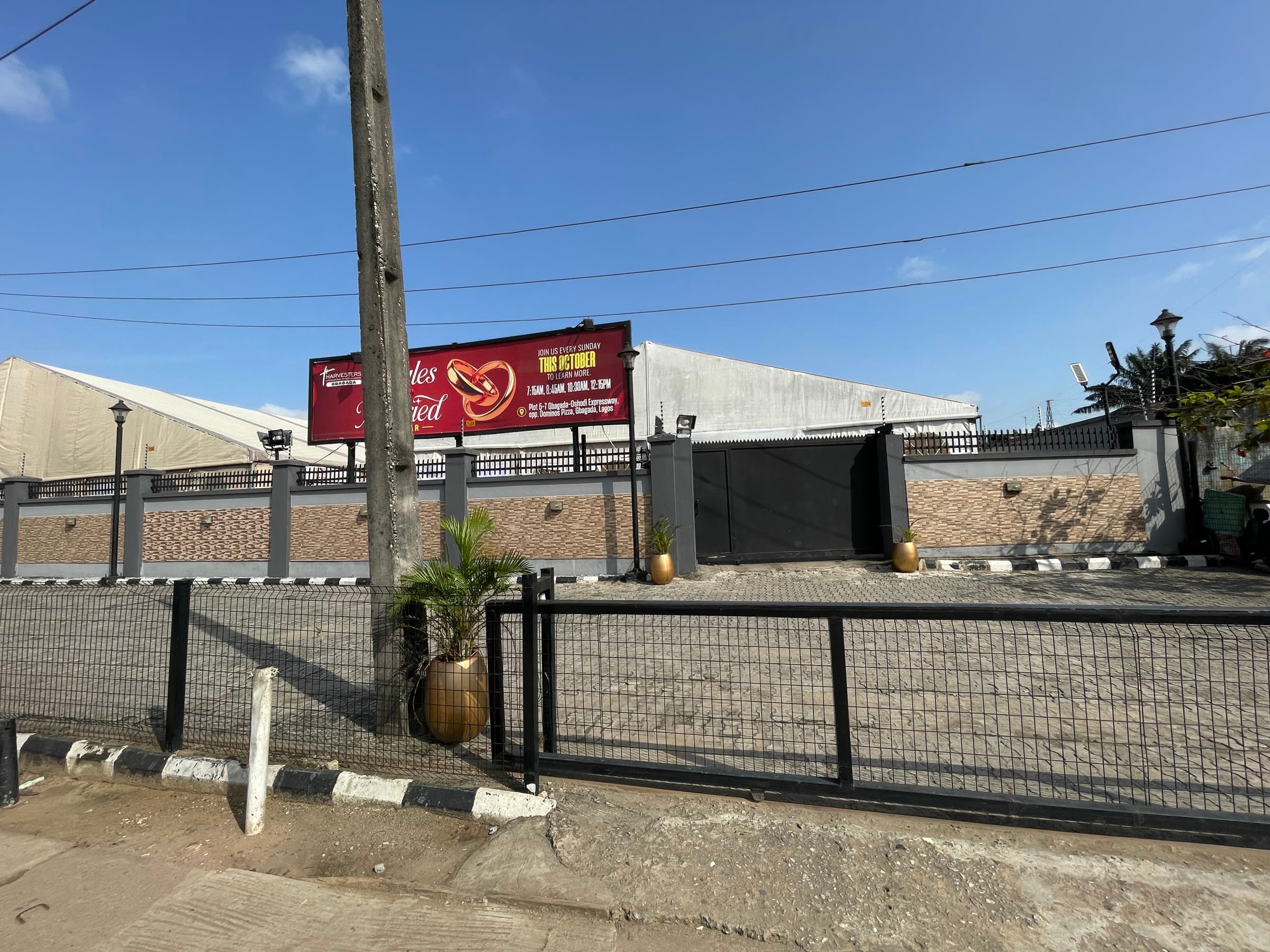 The outside of the venue seen from the road, with the hall behind the gate